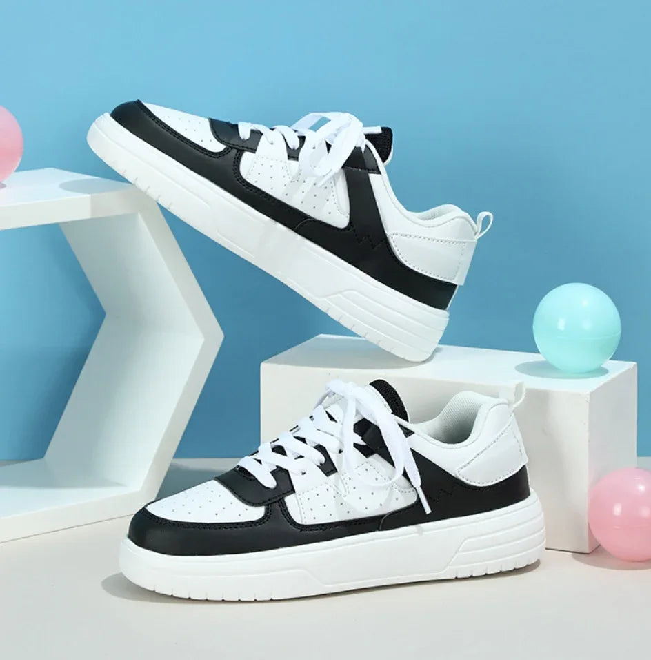 Black and white casual sneakers with white laces displayed on geometric white platforms against a blue background