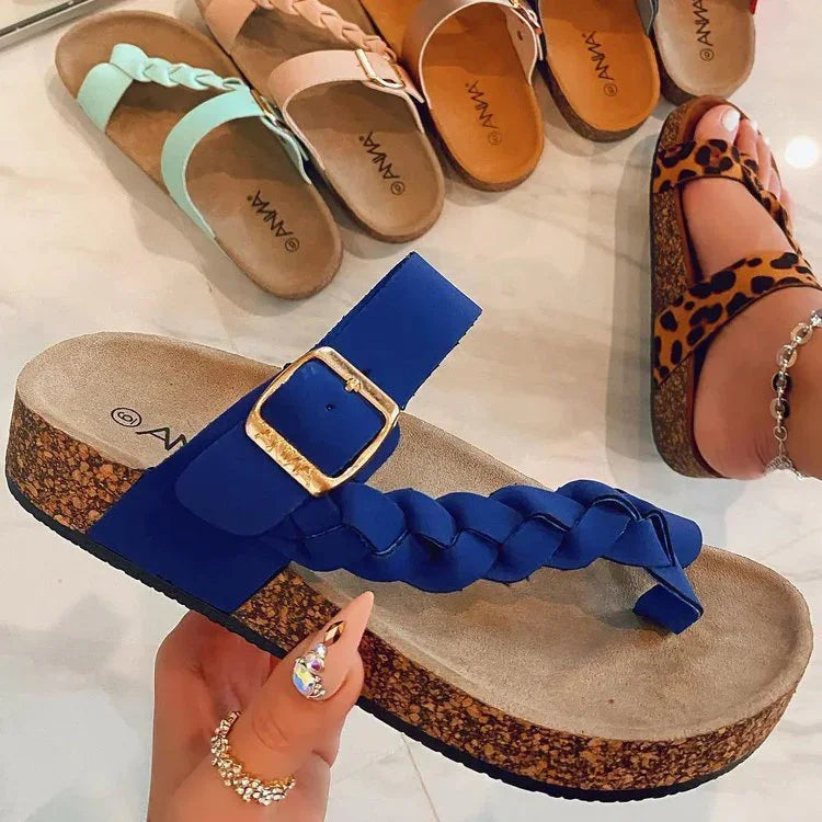 Close-up of blue braided cork wedge sandals with gold buckle and other colorful sandals on white floor