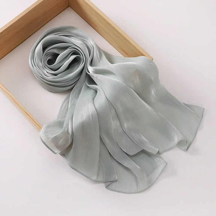 Light gray shimmery silk scarf elegantly displayed in a wooden frame on white background