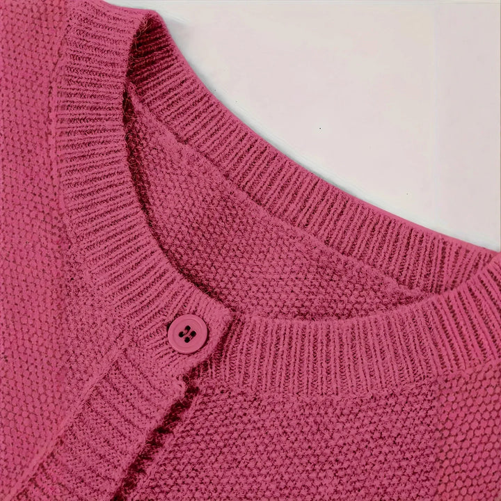 Close-up of pink textured knit sweater collar with ribbed edges and button detail
