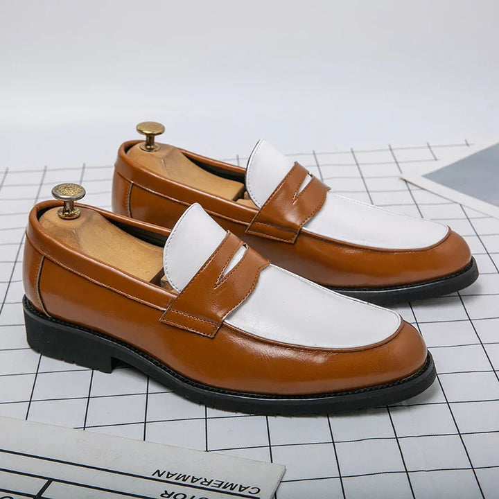 Brown and white leather men's loafers with black soles on grid surface