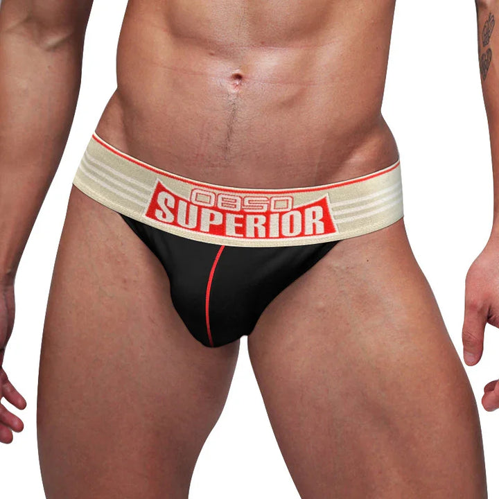 Male model wearing black jockstrap underwear with beige waistband labeled OBSESSO SUPERIOR