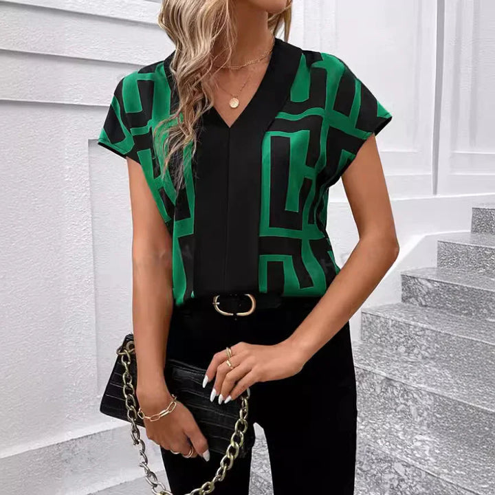 Woman wearing black and green geometric print blouse with black pants and chain purse
