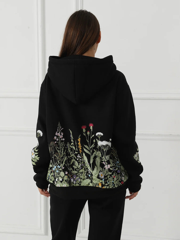 Rear view of woman wearing black hoodie with colorful wildflower embroidery on back and sleeves