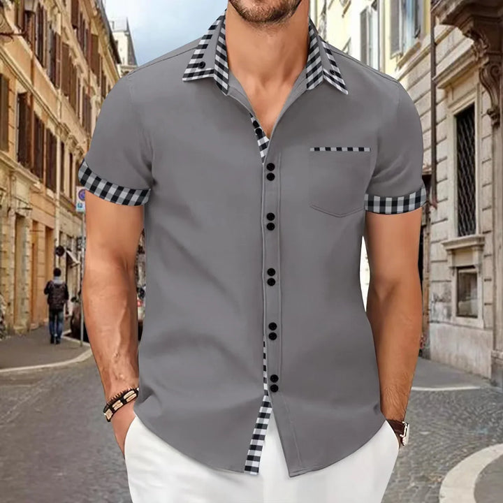 Man wearing stylish grey short-sleeve button-up shirt with black and white checkered collar and sleeve cuffs on city street