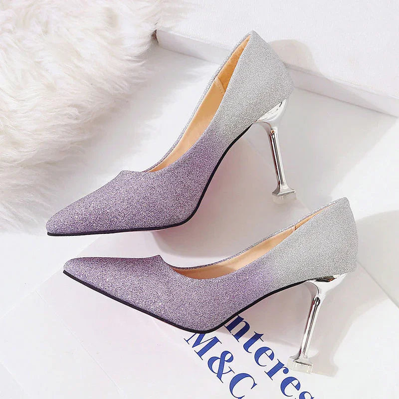 Pair of gradient purple to silver glitter high heel pumps with metallic stiletto heels on white surface