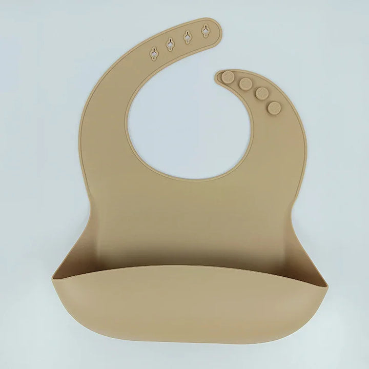Beige silicone baby bib with adjustable snap buttons and food-catching pocket on white background
