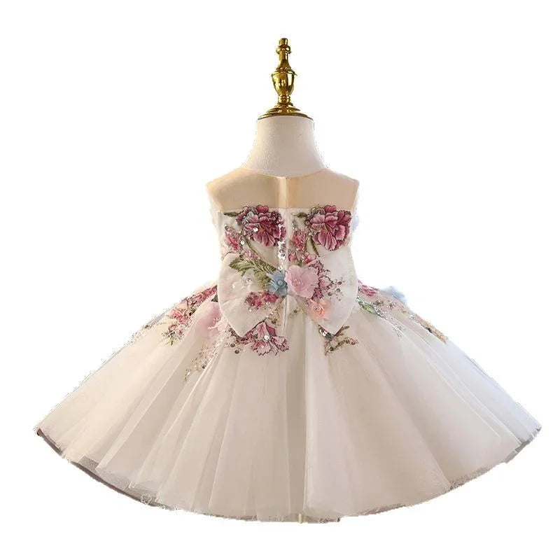 White tulle toddler dress with pink floral embroidery and large bow on mannequin