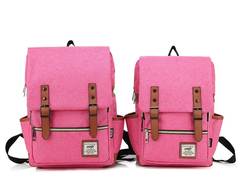 Two pink fabric backpacks with brown leather straps, front zipper pockets, and black adjustable shoulder straps