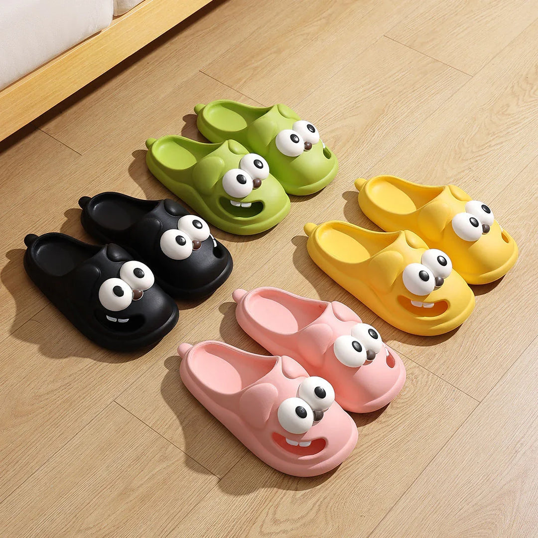 Colorful kids slip-on slippers with cartoon eyes and teeth in black, green, yellow, and pink on wood floor