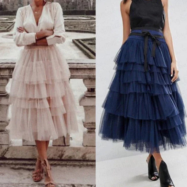 Two women wearing layered tulle midi skirts, one in light pink with a white blouse and sandals, the other in navy blue with a black top and black heels