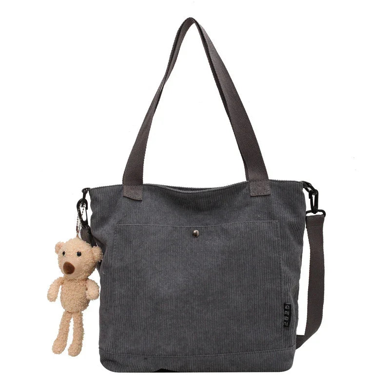 Dark gray corduroy tote bag with long handles and small beige teddy bear keychain