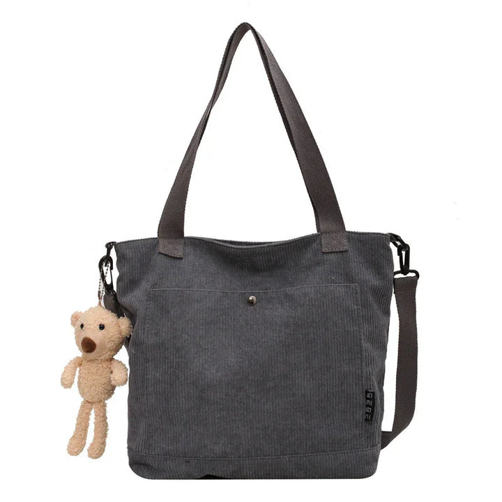 Dark gray corduroy tote bag with long handles and small beige teddy bear keychain