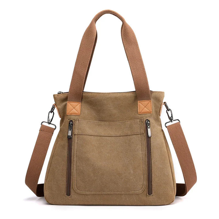 Brown canvas tote bag with dual zippered front pockets and adjustable shoulder strap