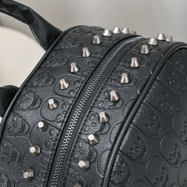 Black leather bag with embossed skull pattern and silver metal studs close-up