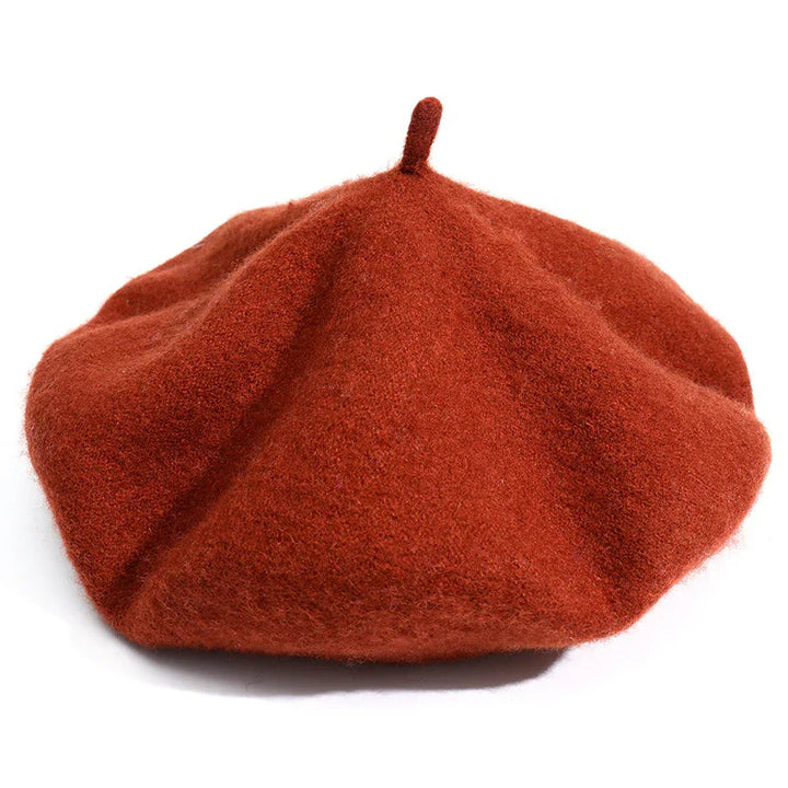 Rust orange wool beret with a small top stem on a white background