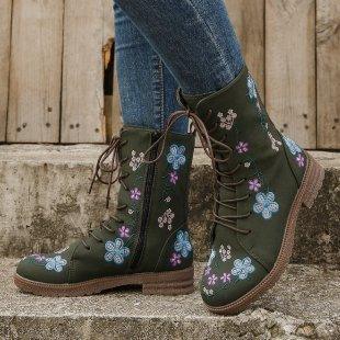 Green lace-up ankle boots with blue and pink floral embroidery worn with cuffed jeans on stone steps