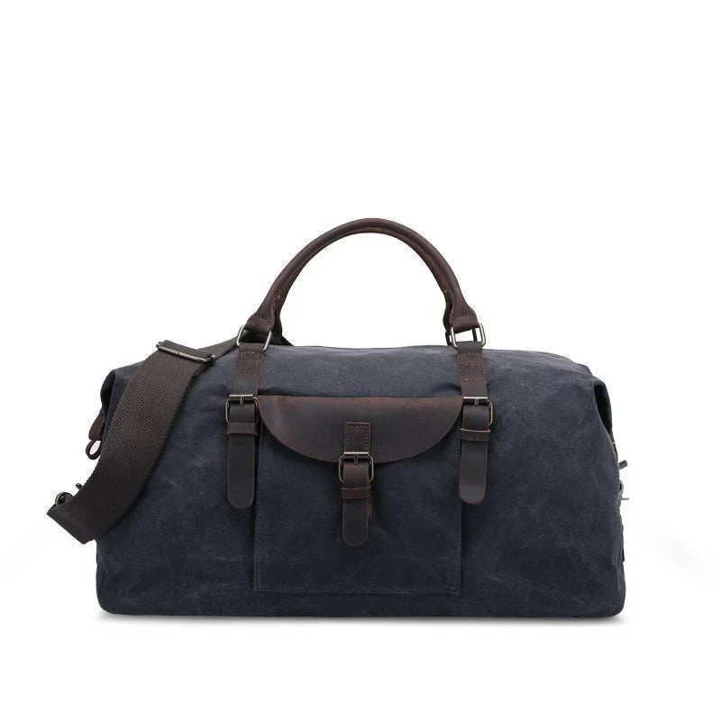 Dark blue canvas duffle bag with brown leather handles and front buckle pocket, adjustable shoulder strap