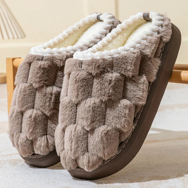 Pair of cozy brown faux fur slippers with plush white lining on beige carpet