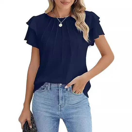 woman wearing navy blue pleated blouse and light blue jeans holding black purse
