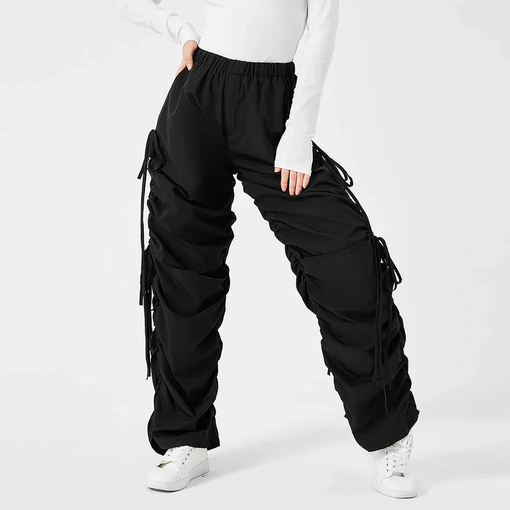Black ruched cargo pants with drawstring details worn with white sneakers and white long sleeve top