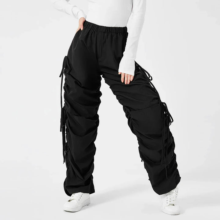 Black ruched cargo pants with drawstring details worn with white sneakers and white long sleeve top