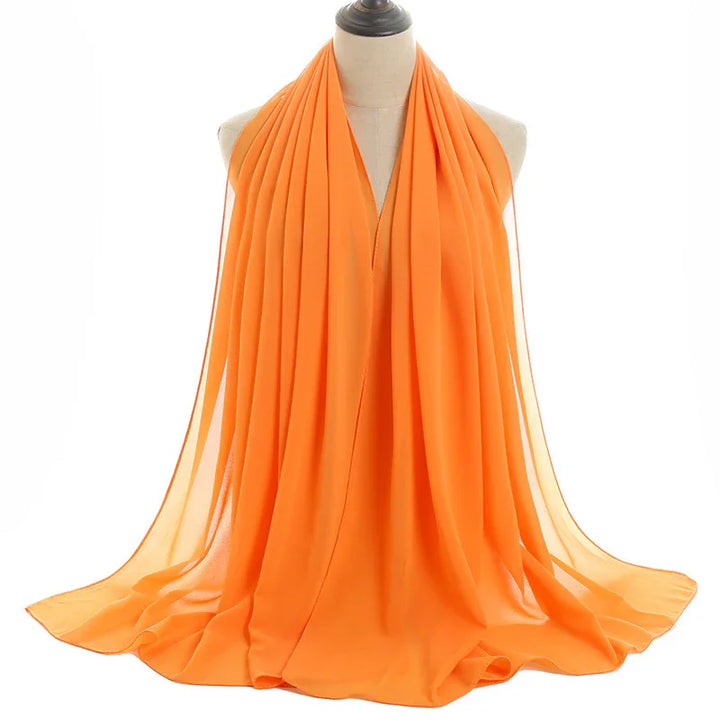Bright orange chiffon scarf draped on beige dress form with soft pleats