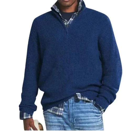 Man wearing a navy blue quarter-zip sweater over a plaid shirt with blue jeans