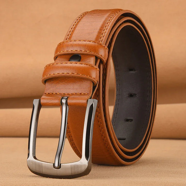 Brown leather belt with silver buckle rolled on tan background