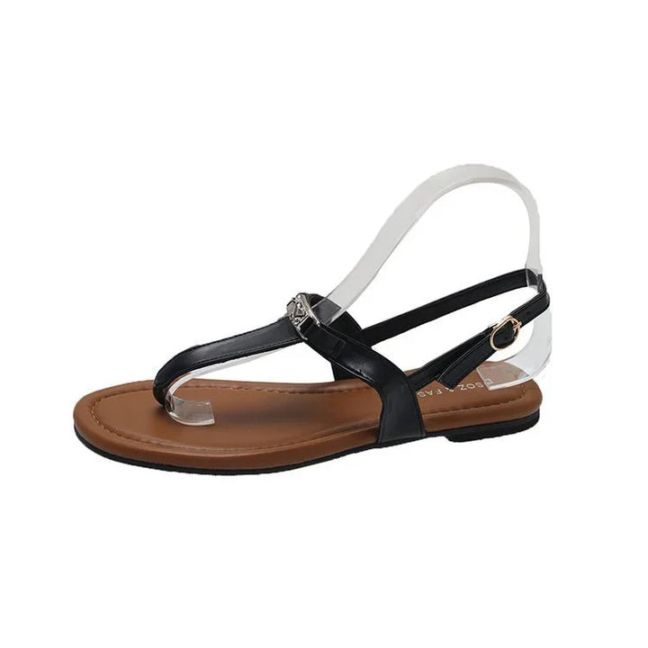 Black leather flat thong sandal with brown cushioned sole and adjustable ankle strap