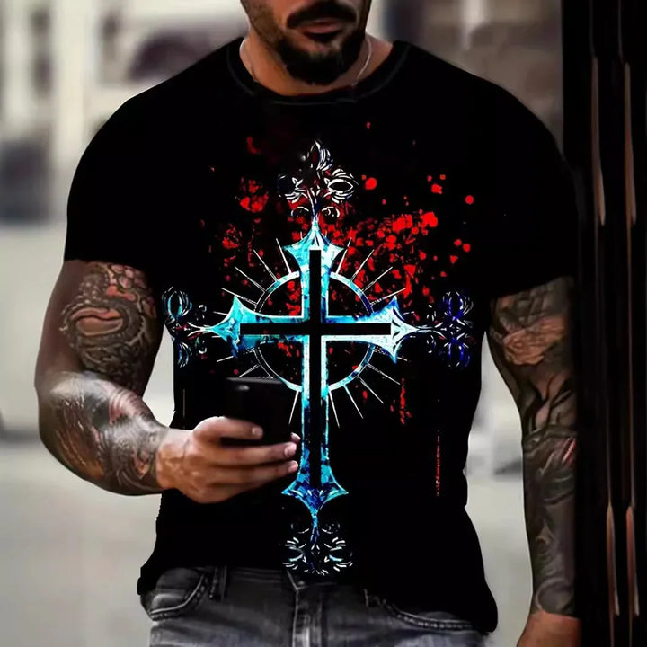 Man wearing black t-shirt with blue cross and red splatter design, holding phone, tattooed arms