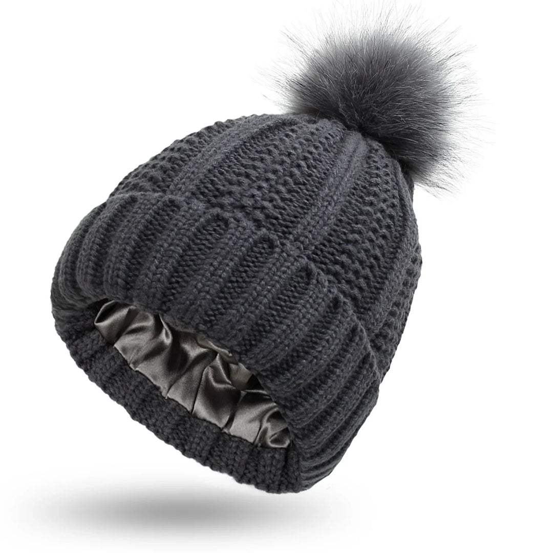 Dark gray knitted winter beanie hat with a faux fur pom-pom and satin-lined interior