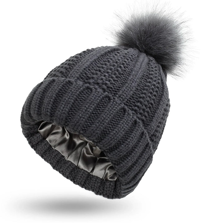 Dark gray knitted winter beanie hat with a faux fur pom-pom and satin-lined interior