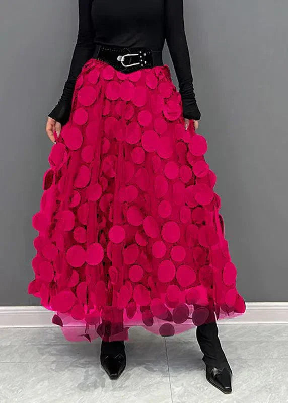 Elegant bright pink maxi skirt with large circular appliques worn with black top and belt