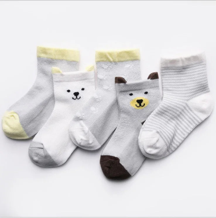 Five pairs of baby socks with animal faces and patterns in white, gray, yellow, and brown on white background