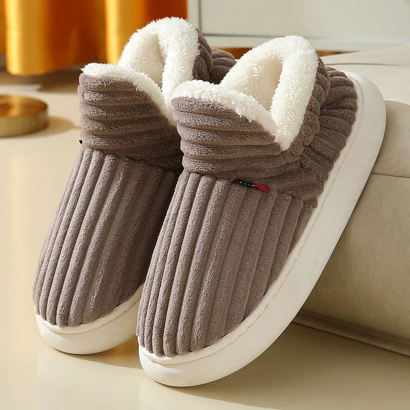 Brown ribbed indoor slippers with white plush lining and thick white soles on beige surface