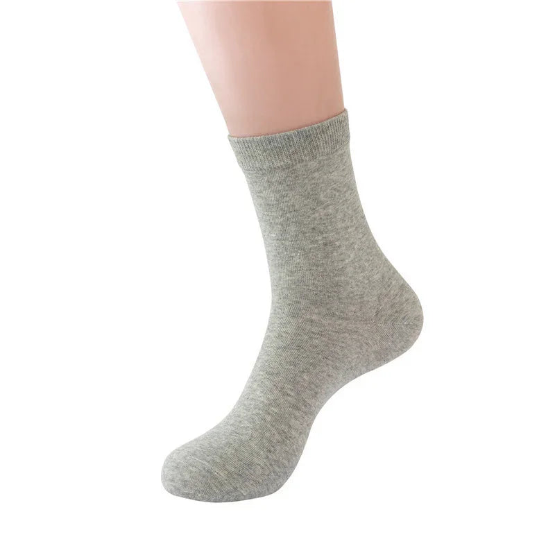 close-up of foot wearing plain light gray mid-calf cotton sock on white background