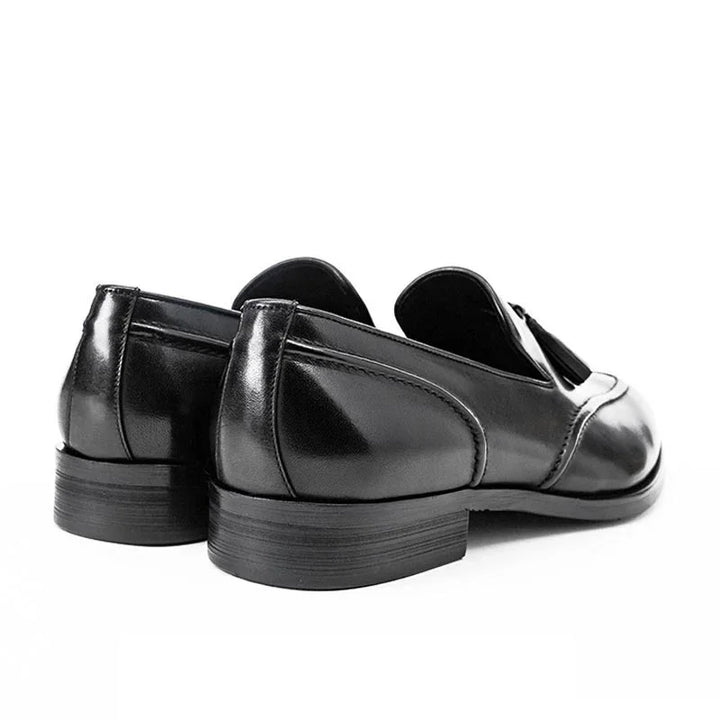 Black leather men's tassel loafers with stacked heels on white background
