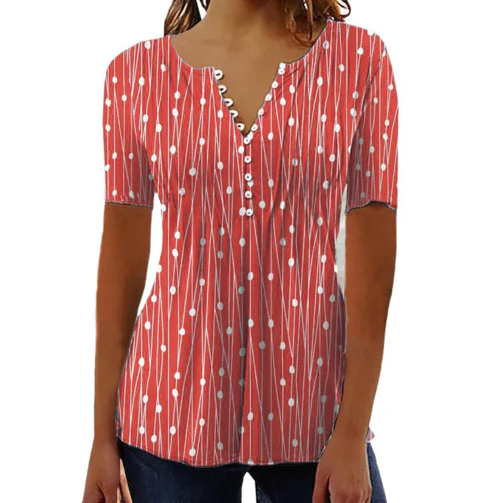 Woman wearing red short-sleeve top with white dot and line pattern, buttoned V-neck, paired with jeans