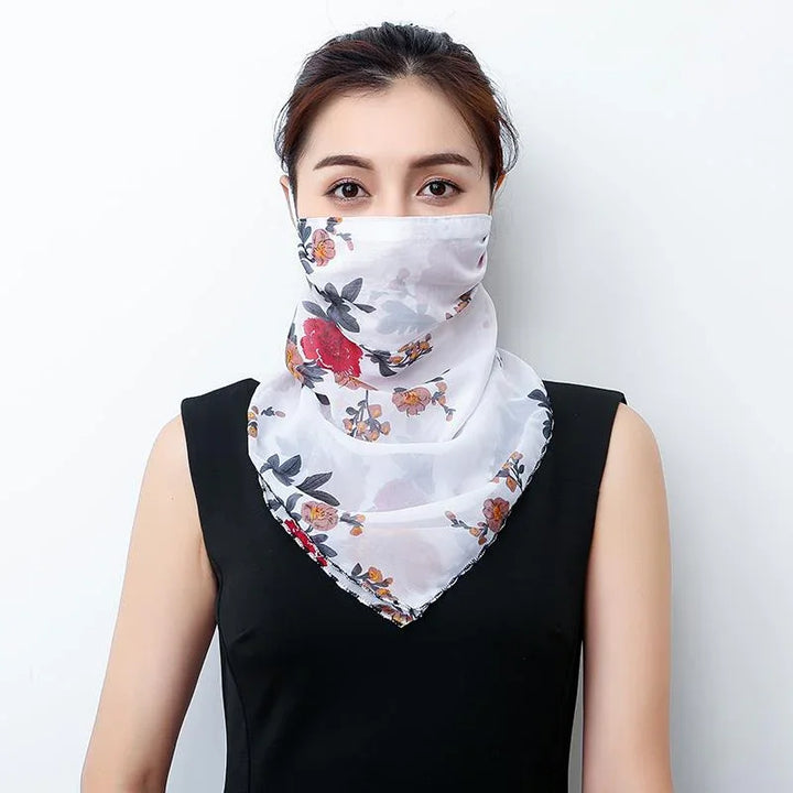 Woman wearing a white floral scarf face covering with red and orange flowers, paired with a black sleeveless top