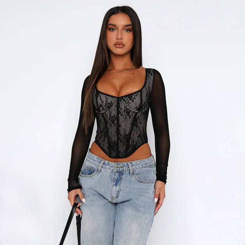 Woman wearing black lace corset top with long sheer sleeves and light blue jeans holding black purse