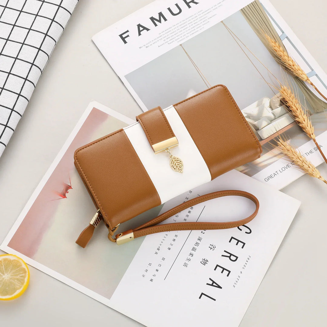 Brown and white leather wristlet wallet with gold leaf charm on magazines and wheat stalks