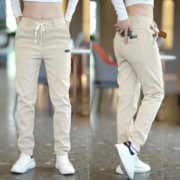Front and side views of woman wearing beige corduroy jogger pants with drawstring and white sneakers indoors