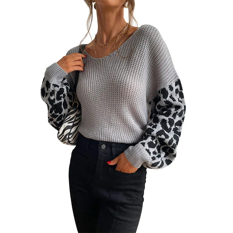 Woman wearing a gray knit sweater with black and white leopard print balloon sleeves and black pants