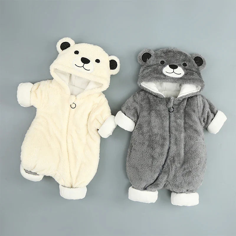 Two plush baby onesies with bear faces on hoods in cream and gray colors on gray background
