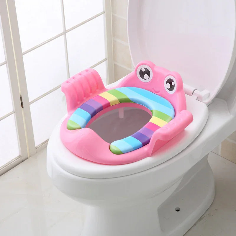 Pink frog-shaped padded children's potty training seat with rainbow cushion on white toilet