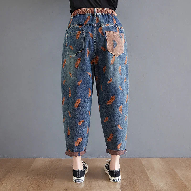 Back view of blue denim pants with orange feather prints and a contrasting pink back pocket