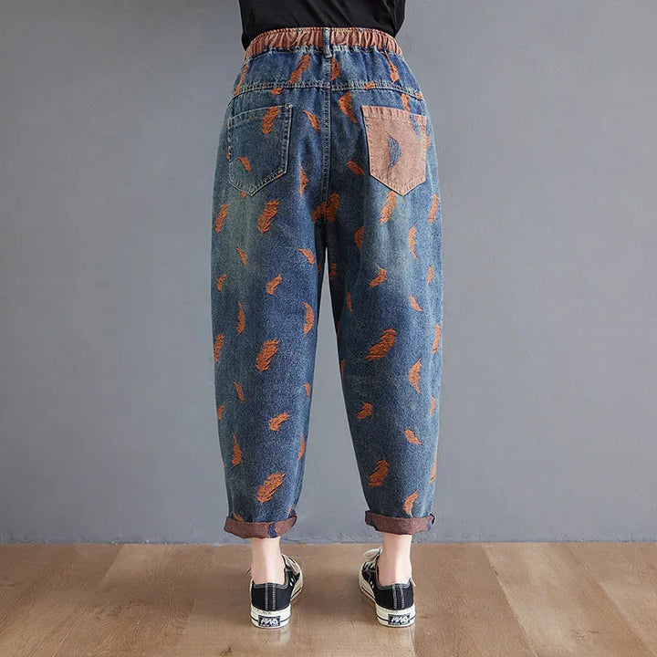 Back view of blue denim pants with orange feather prints and a contrasting pink back pocket
