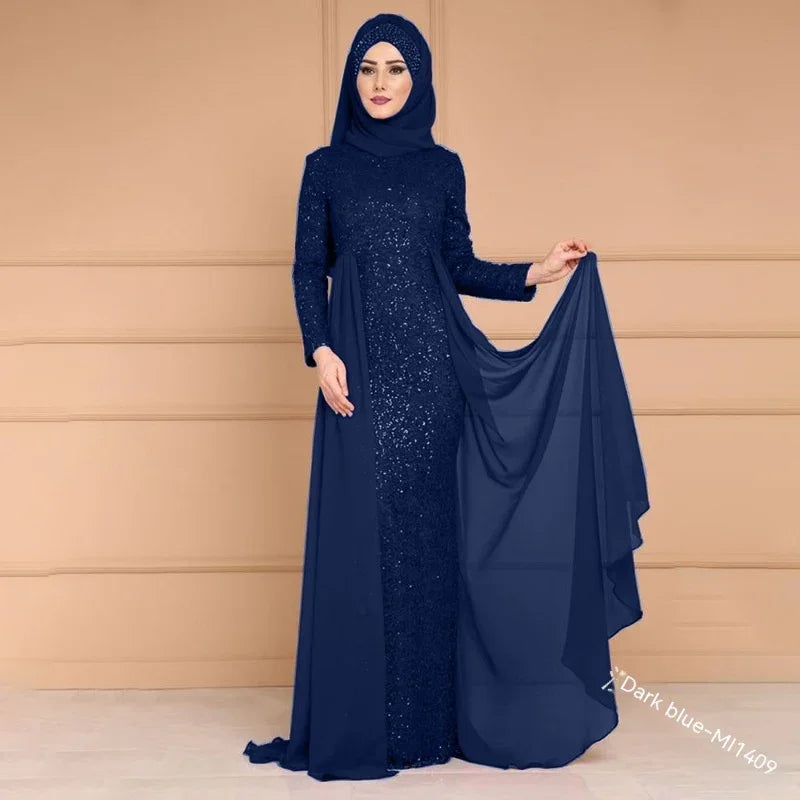 Woman wearing a dark blue sequined long dress with matching hijab holding fabric in neutral indoor setting