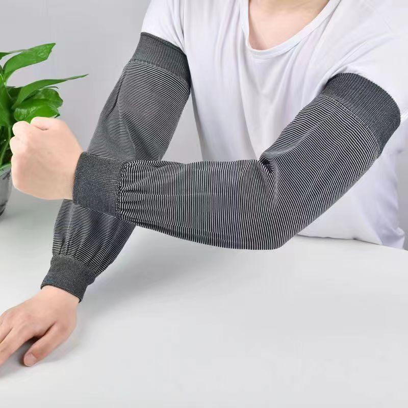 Person wearing black and white striped arm sleeves over a white shirt, sitting at a white table with a green plant nearby